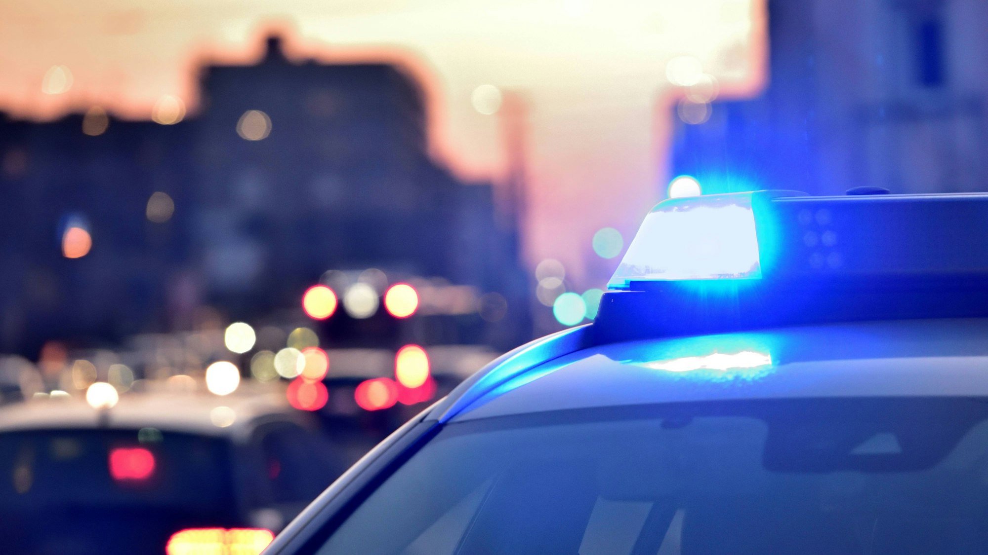 Das Bild zeigt ein Blaulicht auf einem Streifenwagen leuchtet.