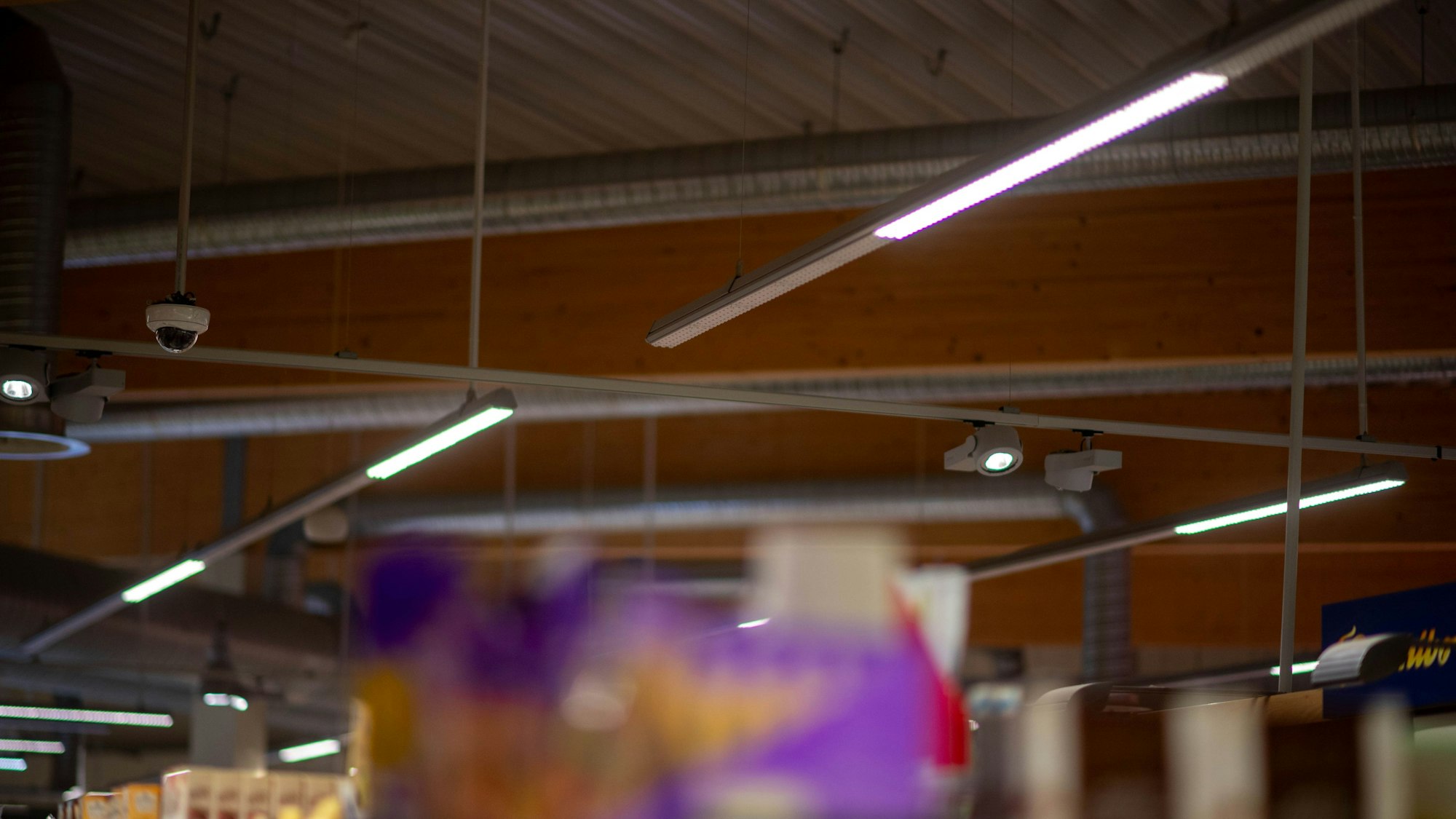 Die Deckenbeleuchtung in einem Supermarkt ist weniger hell eingeschaltet als gewohnt.