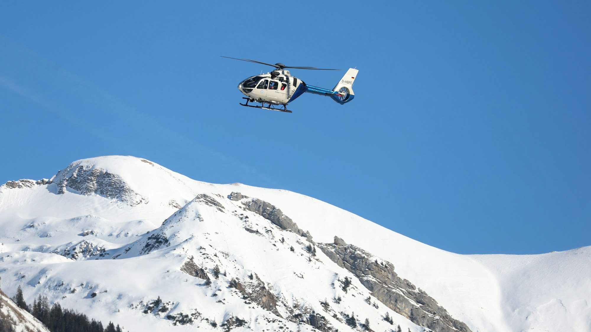14.01.2024, Bayern, Oberstdorf: Ein Hubschrauber der Polizei fliegt nach einem Lawinenabgang über den Bergen. Foto: Karl-Josef Hildenbrand/dpa +++ dpa-Bildfunk +++