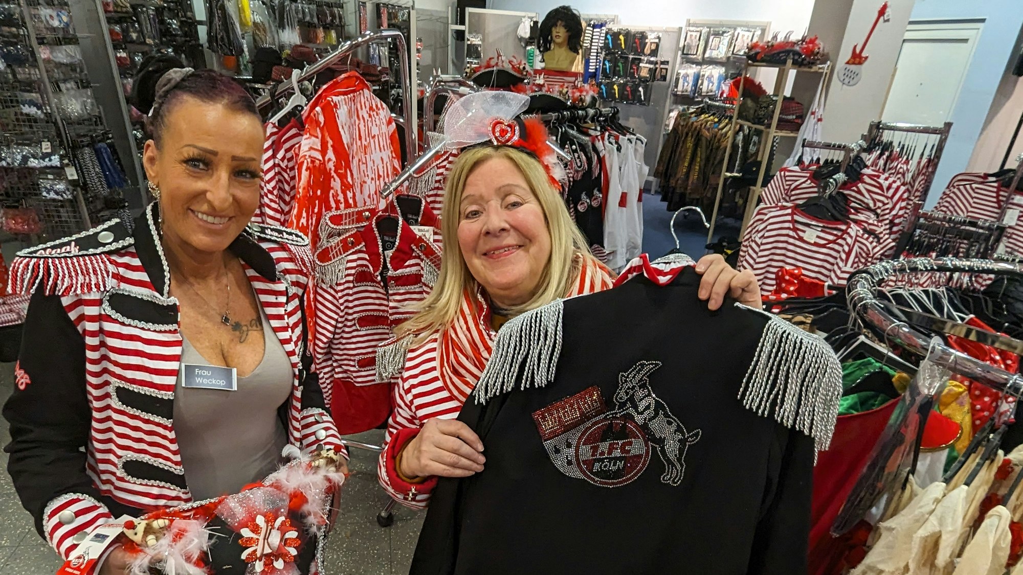 Zwei kostümierte Frauen zeigen Hut und Jacke im Karnevalsladen im Hürth-Park.