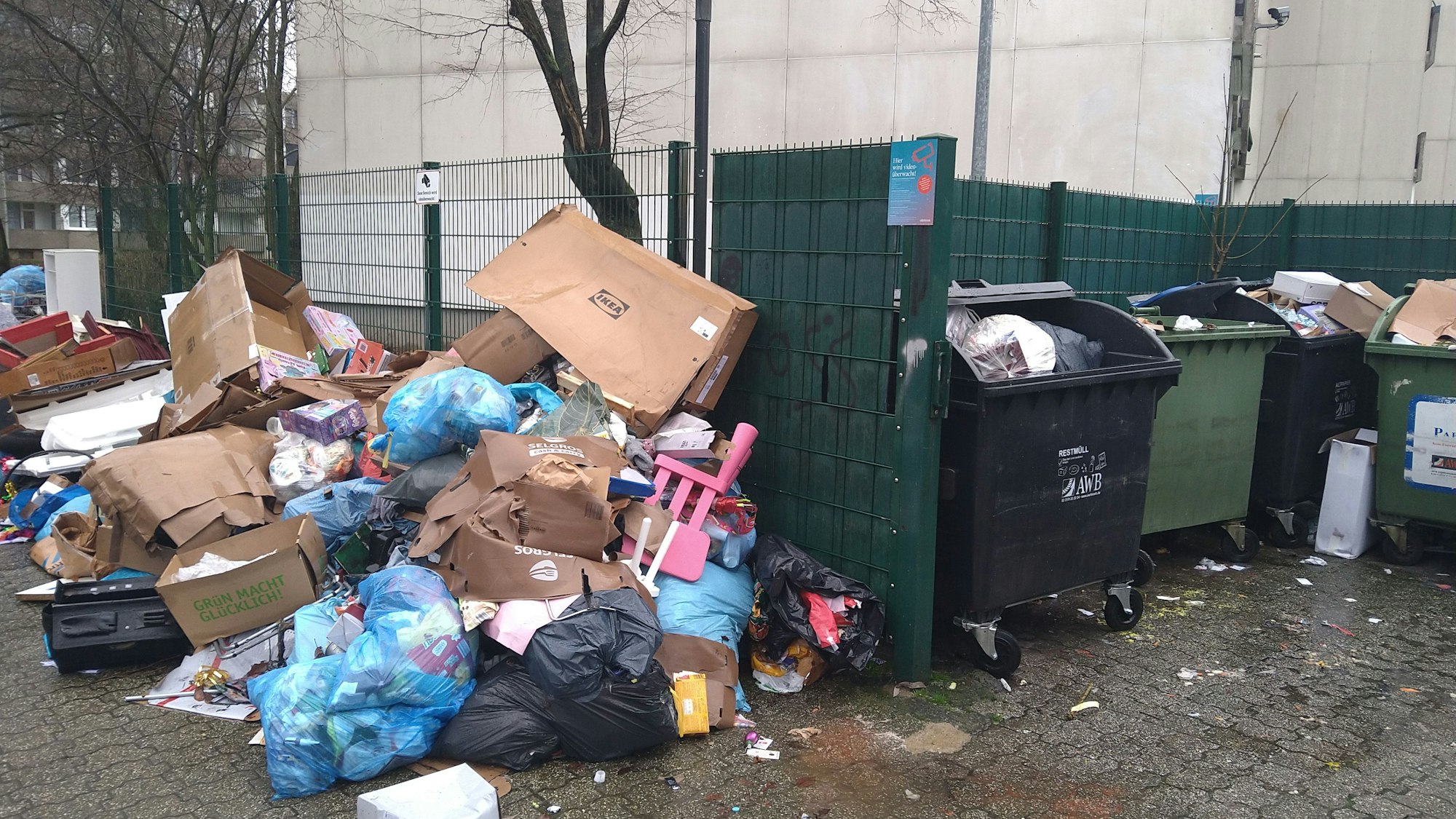 Neben den regulären Mülltonnen, die bis oben voll sind, hat sich ein Berg aus Müll und Sperrmüll gebildet.