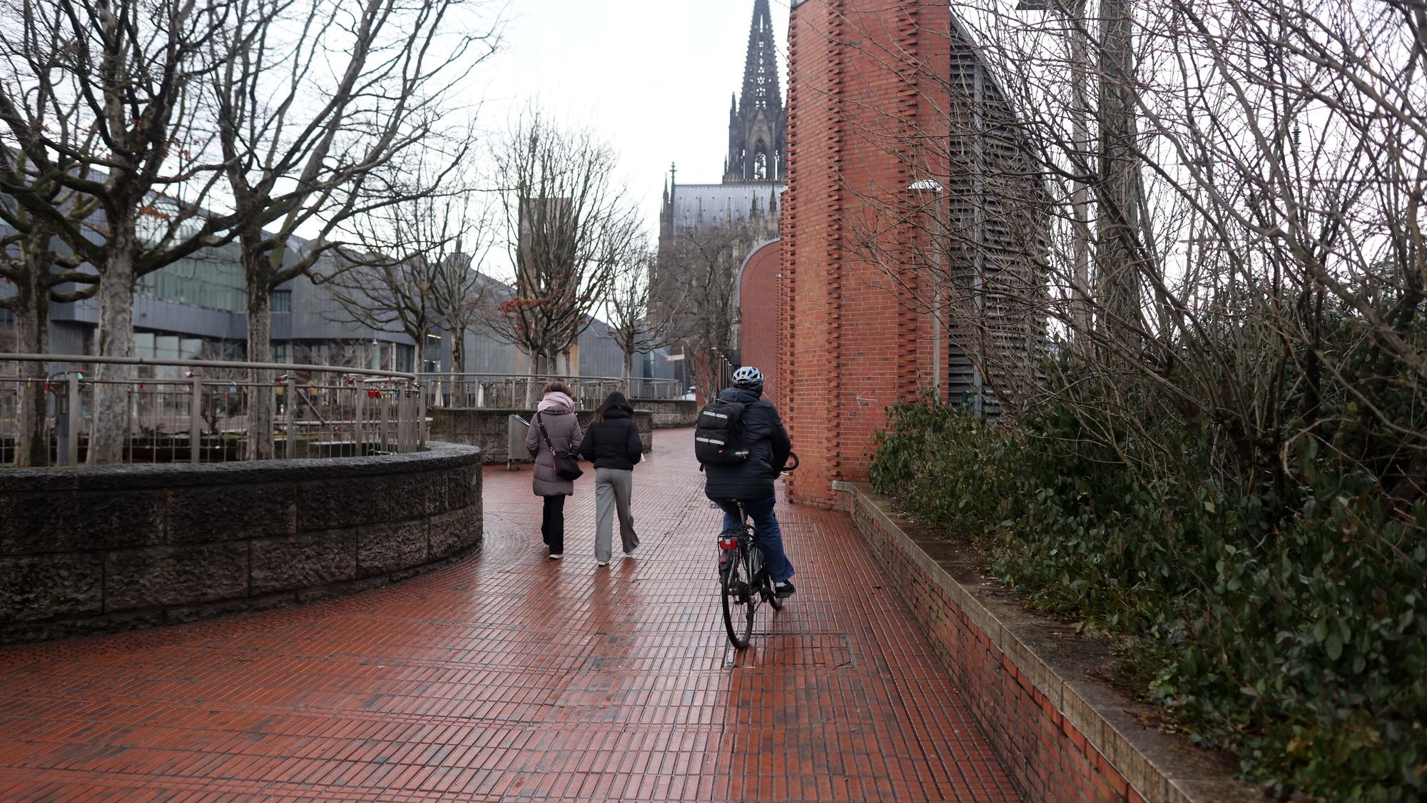Fußgänger und ein Radfahrer sind auf dem Weg Richtung Dom.
