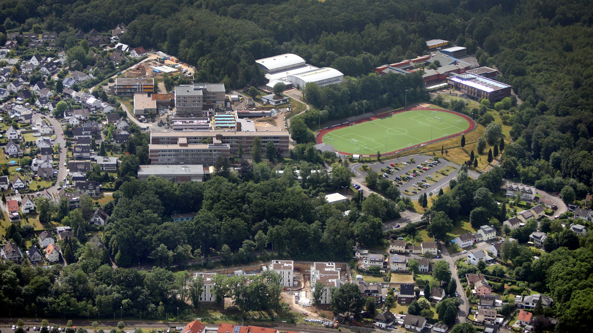 In Rösrath soll zwischen Gesamtschule, Wald und der Straße „An der Foche“ ein weiteres Gesamtschul-Gebäude mit Aula entstehen (oben im Bild).