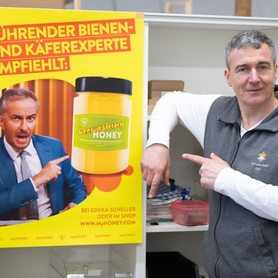 Rico Heinzig, Imker, steht neben einem Plakat mit dem Foto des Moderators Jan Böhmermann. Böhmermann verklagt den Imker.