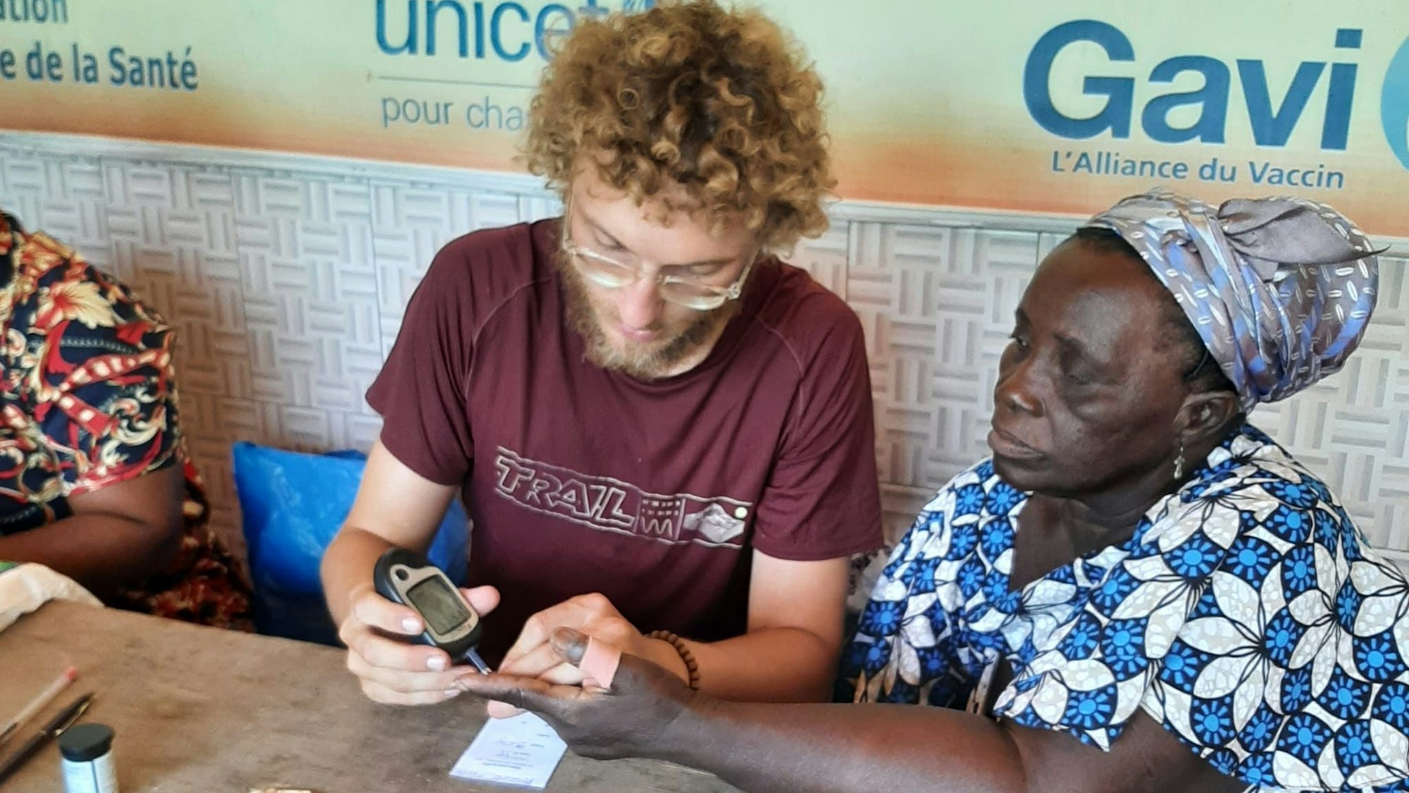 Ein junger Mann misst die Blutwerte einer Frau.