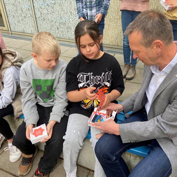 Auf einer Bank sitzen Kinder neben einem Mann.