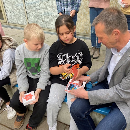 Auf einer Bank sitzen Kinder neben einem Mann.