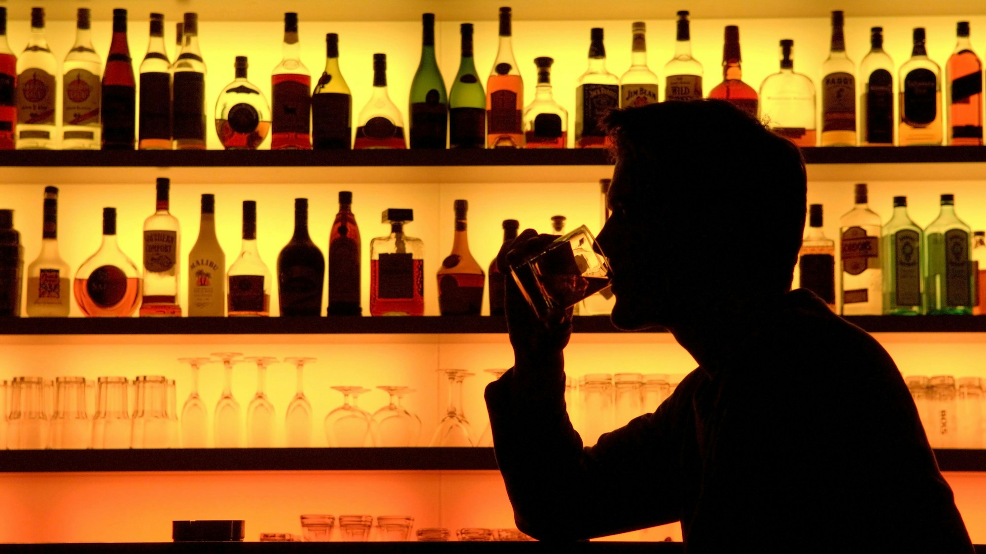 Ein Bar-Besucher sitzt vor einer bunt beleuchteten Bar. (Symbolfoto)