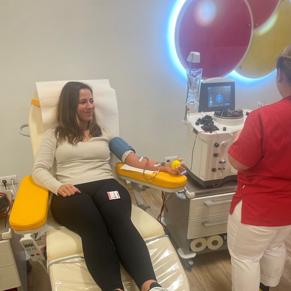 Eine Frau sitz auf einem Stuhl und spendet Blut.