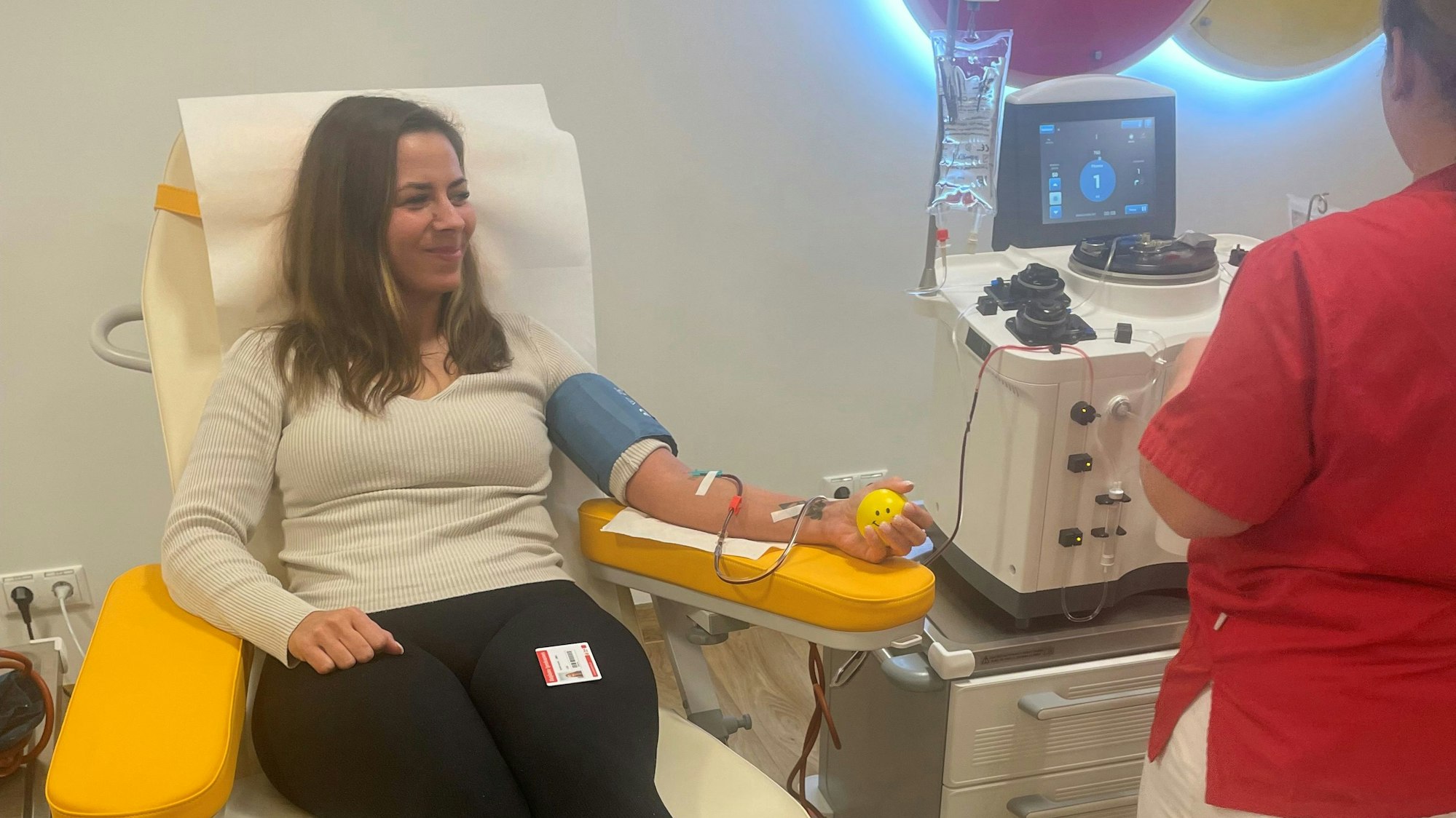 Eine Frau sitz auf einem Stuhl und spendet Blut.