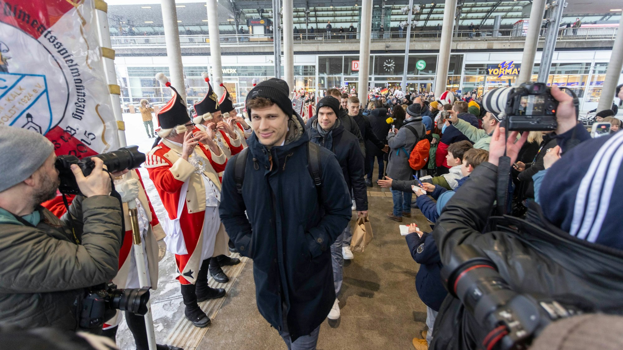 Ankunft mit voller Kapelle: Die Roten Funken grüßen das Handball-Team mit Lukas Mertens.