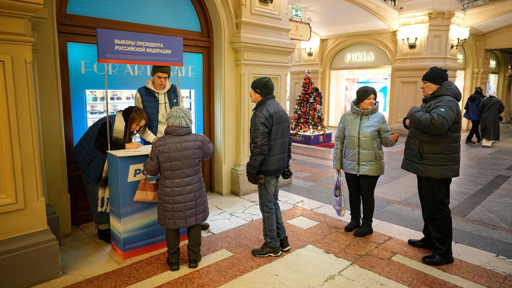 Freiwillige der Partei „Einiges Russland“ (l) helfen Besuchern während einer Unterschriftensammlung für die Kandidatur des russischen Präsidenten Putin bei den Präsidentschaftswahlen im März.