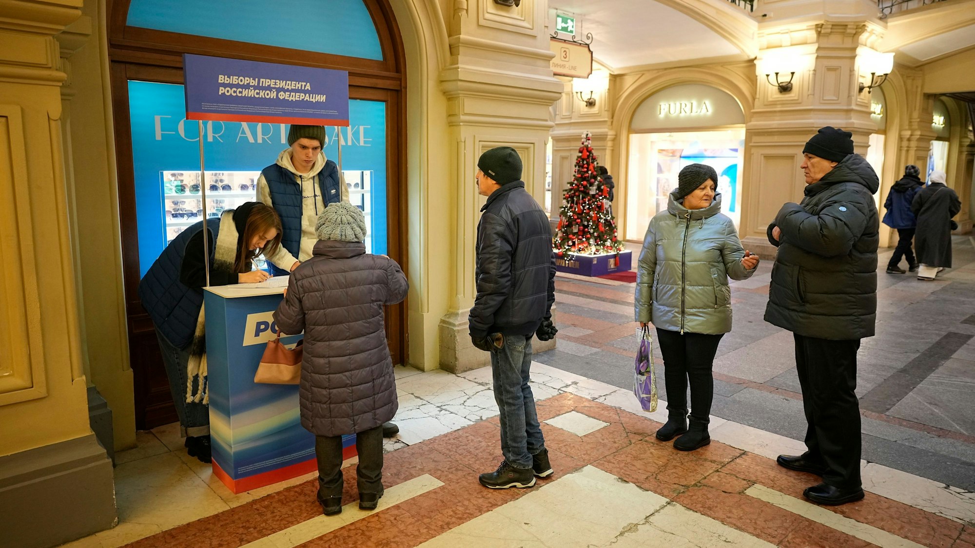 Freiwillige der Partei „Einiges Russland“ (l) helfen Besuchern während einer Unterschriftensammlung für die Kandidatur des russischen Präsidenten Putin bei den Präsidentschaftswahlen im März.