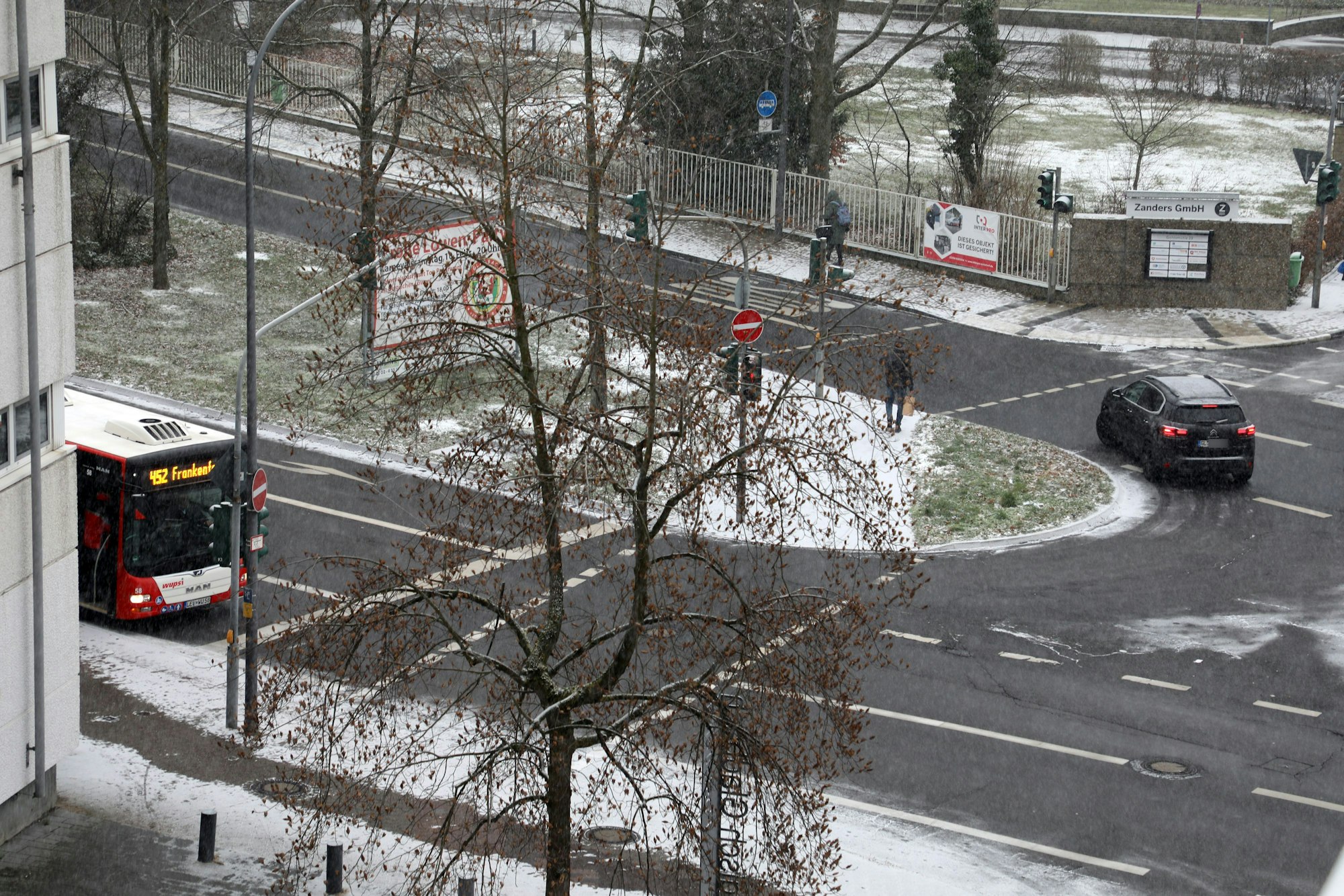 An der Straßenecke An der Gohrsmühle/Poststraße hält ein Bus, ein Auto fährt auf der noch weitgehend schneefreien Fahrbahn.