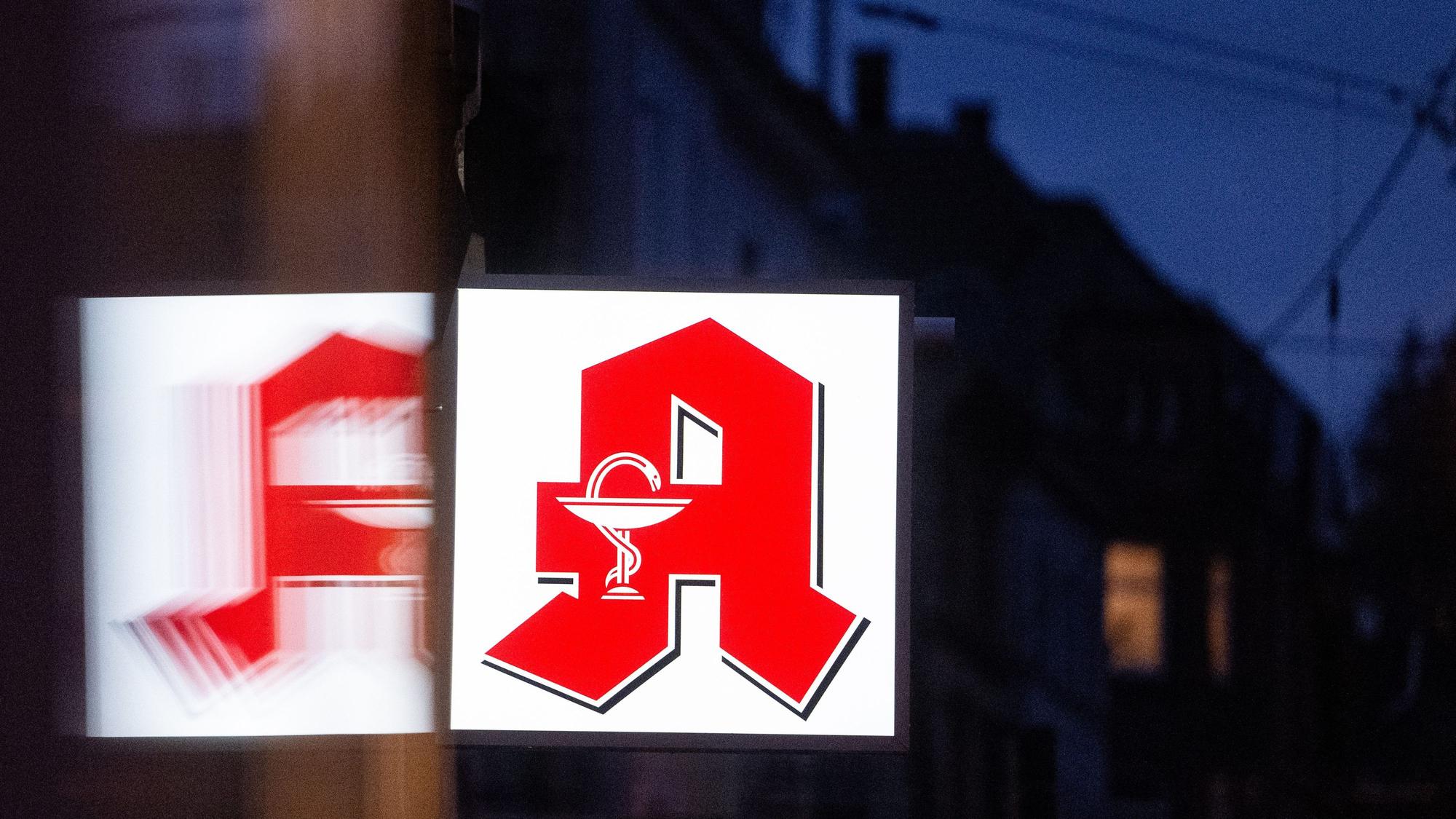 Ein Apothekenschild leuchtet an der Fassade eines Gebäudes in der Innenstadt.