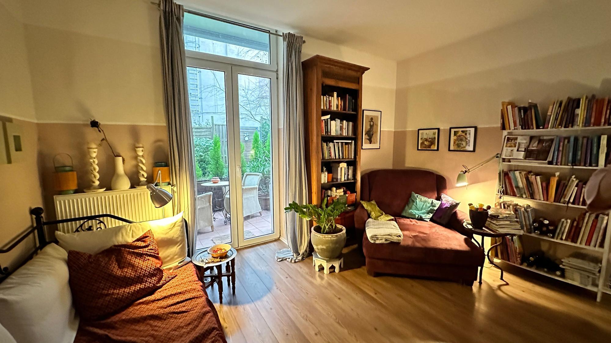 Blick in ein schön aufgeräumtes Wohnzimmer mit tiefen Fenstern, die auf eine Terrasse hinausgehen.