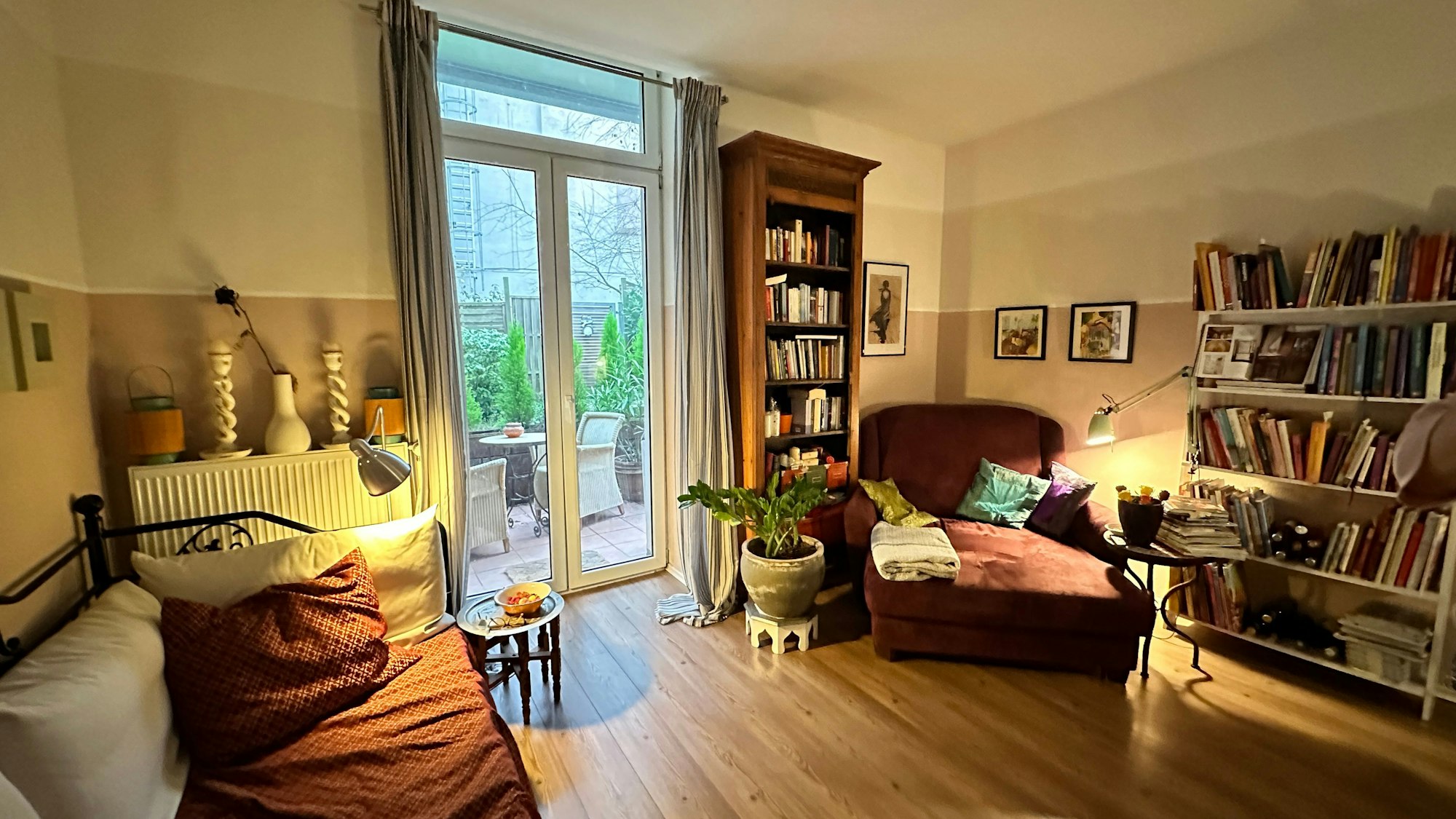 Blick in ein schön aufgeräumtes Wohnzimmer mit tiefen Fenstern, die auf eine Terrasse hinausgehen.