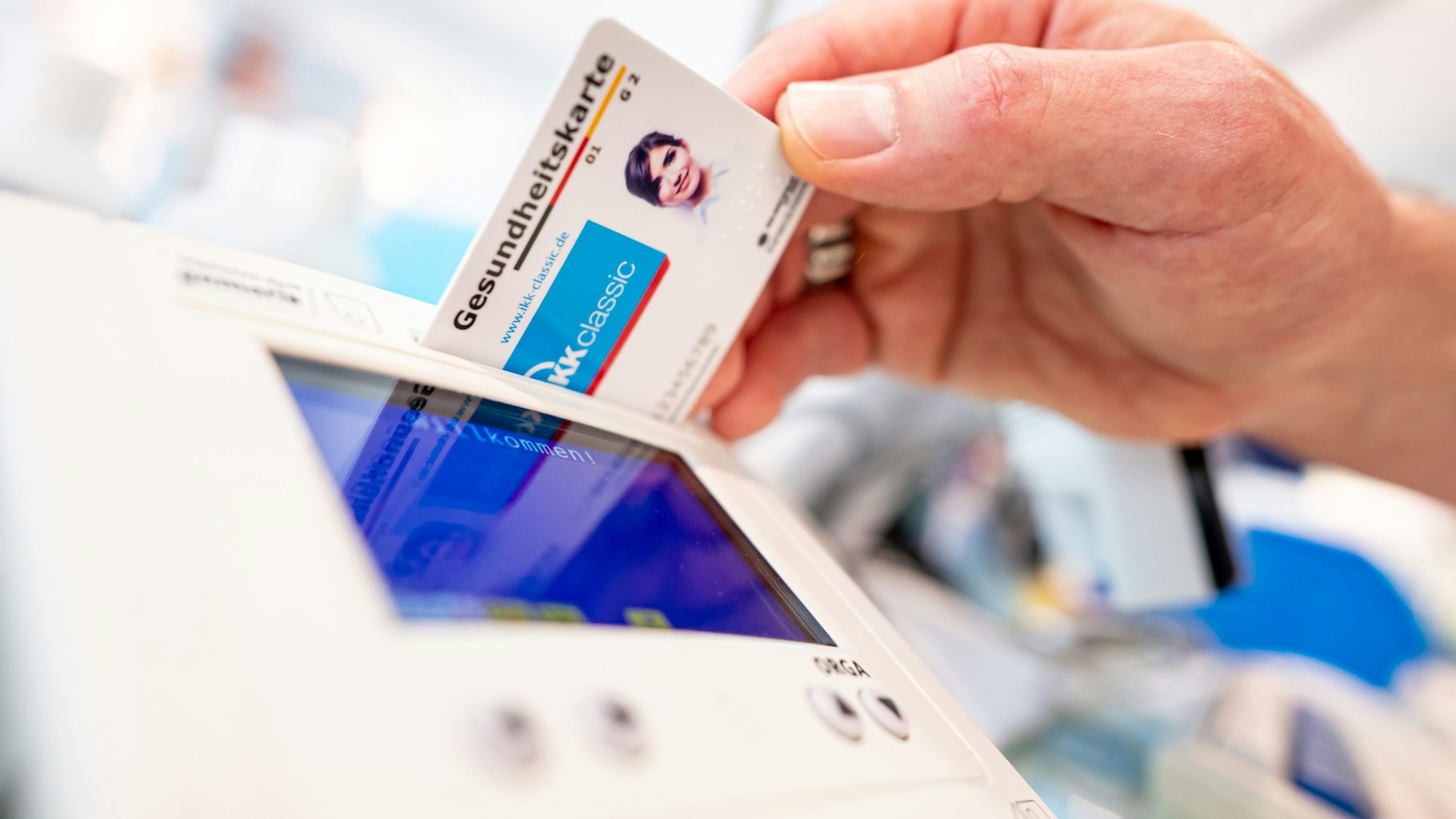 Ein Mitarbeiter einer Apotheke steckt eine Gesundheitskarte in ein Lesegerät.