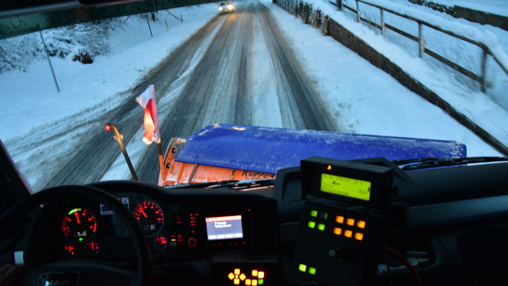 Winterdienst in Much. Der Blick aus dem Führerhaus eines Räumfahrzeugs.