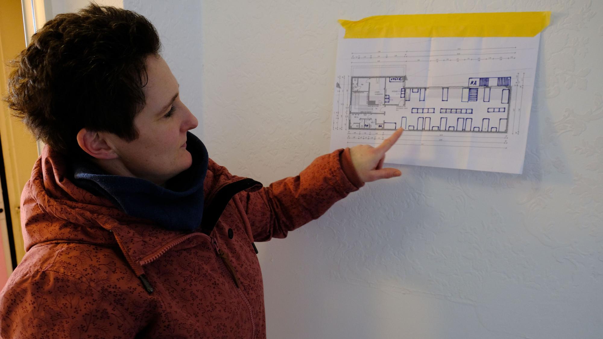 Die zuständige Fachbereichsleiterin Kati Jakob zeigt auf einen Bauplan, der an die Wand gehängt wurde.