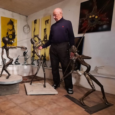 Ein Mann steht neben mehreren feingliedrigen Bronzefiguren.