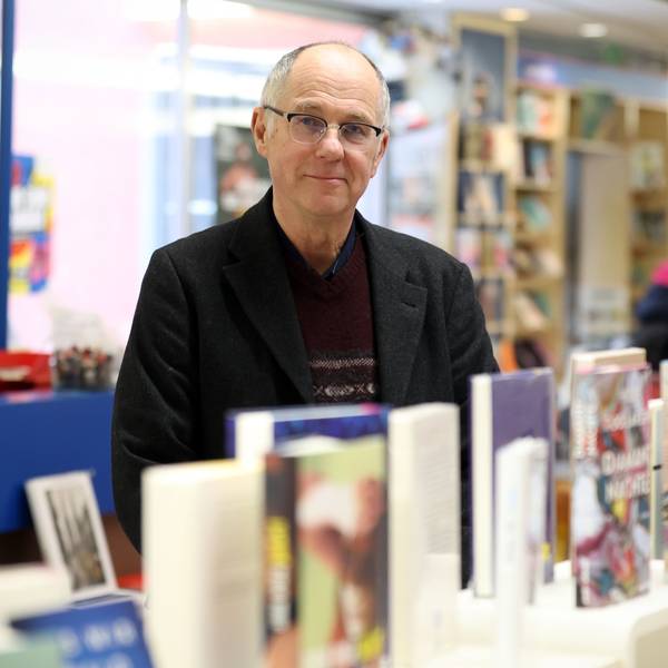 Ein Mann mit Brille steht hinter einem Tisch, auf dem viele Bücher ausgestellt sind.