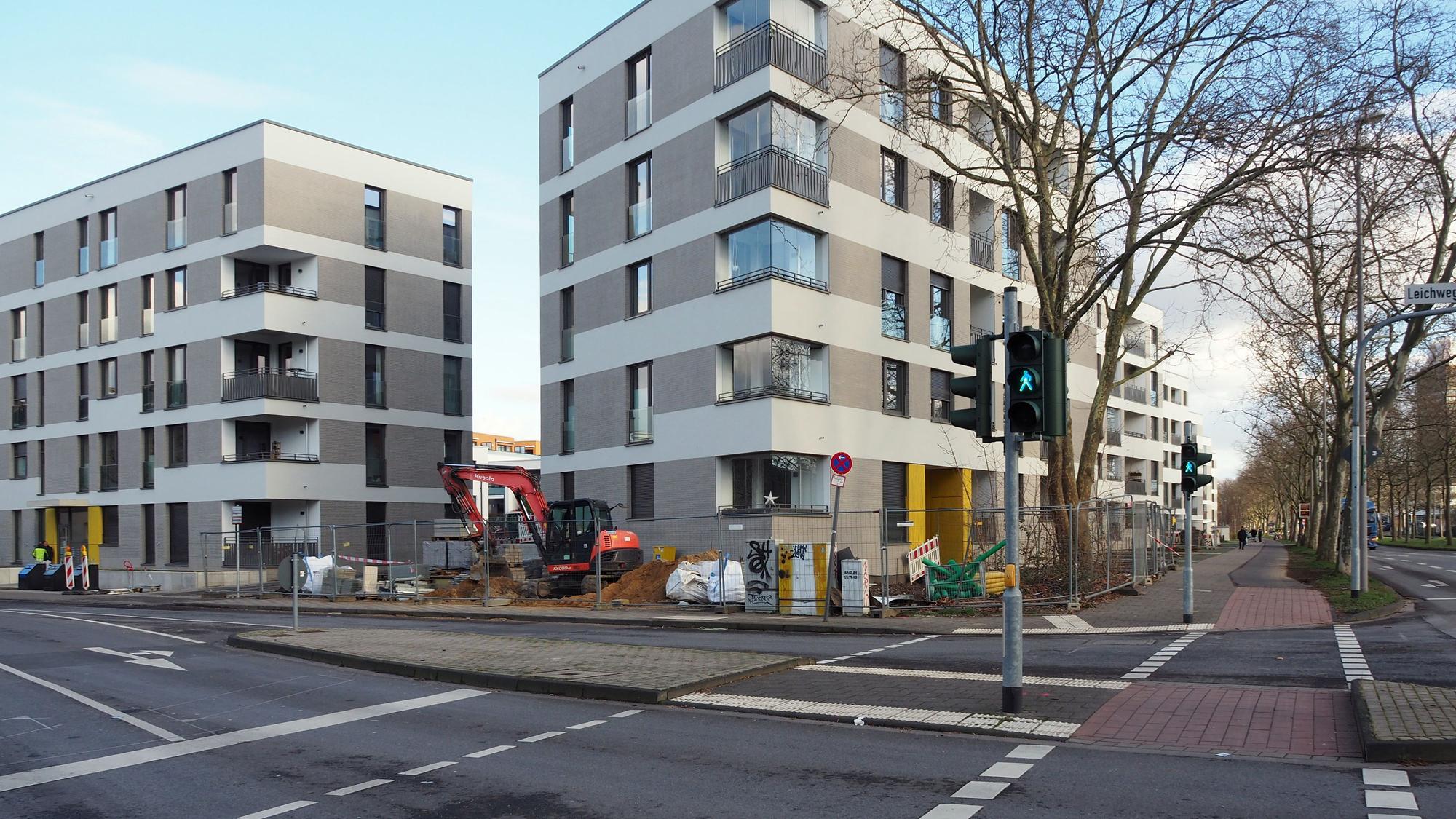 Neue Wohnblöcke, die zum Teil noch mit Bauzäunen abgesperrt sind, liegen direkt an einer großen Kreuzung.