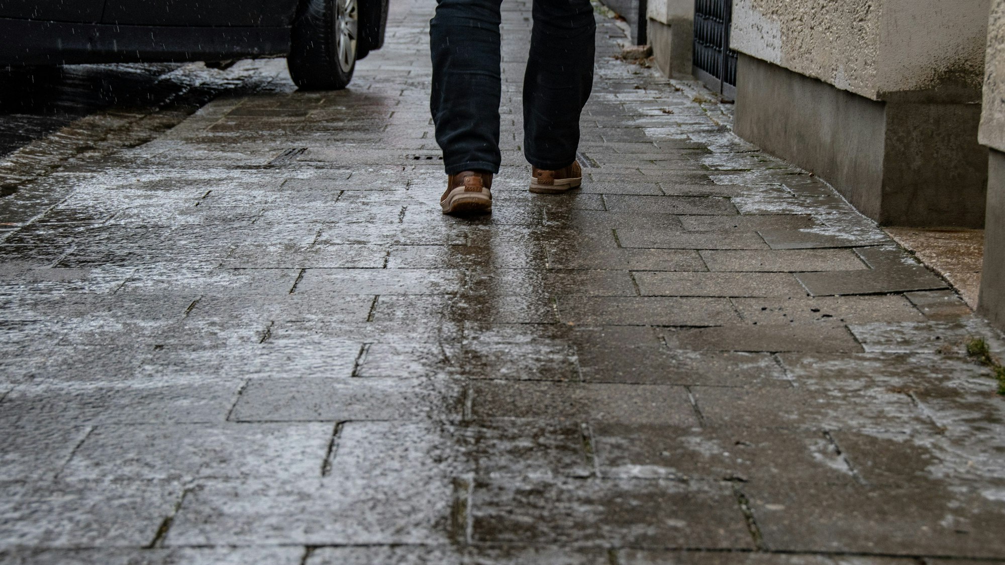 Ein Mann geht auf einem vereisten Gehweg.