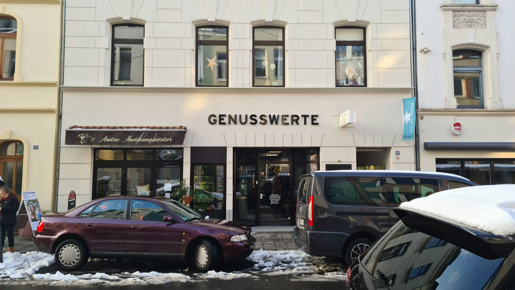 Blick auf ein Ladenlokal im Erdgeschoss eines Altbaus mit geparkten Autos davor