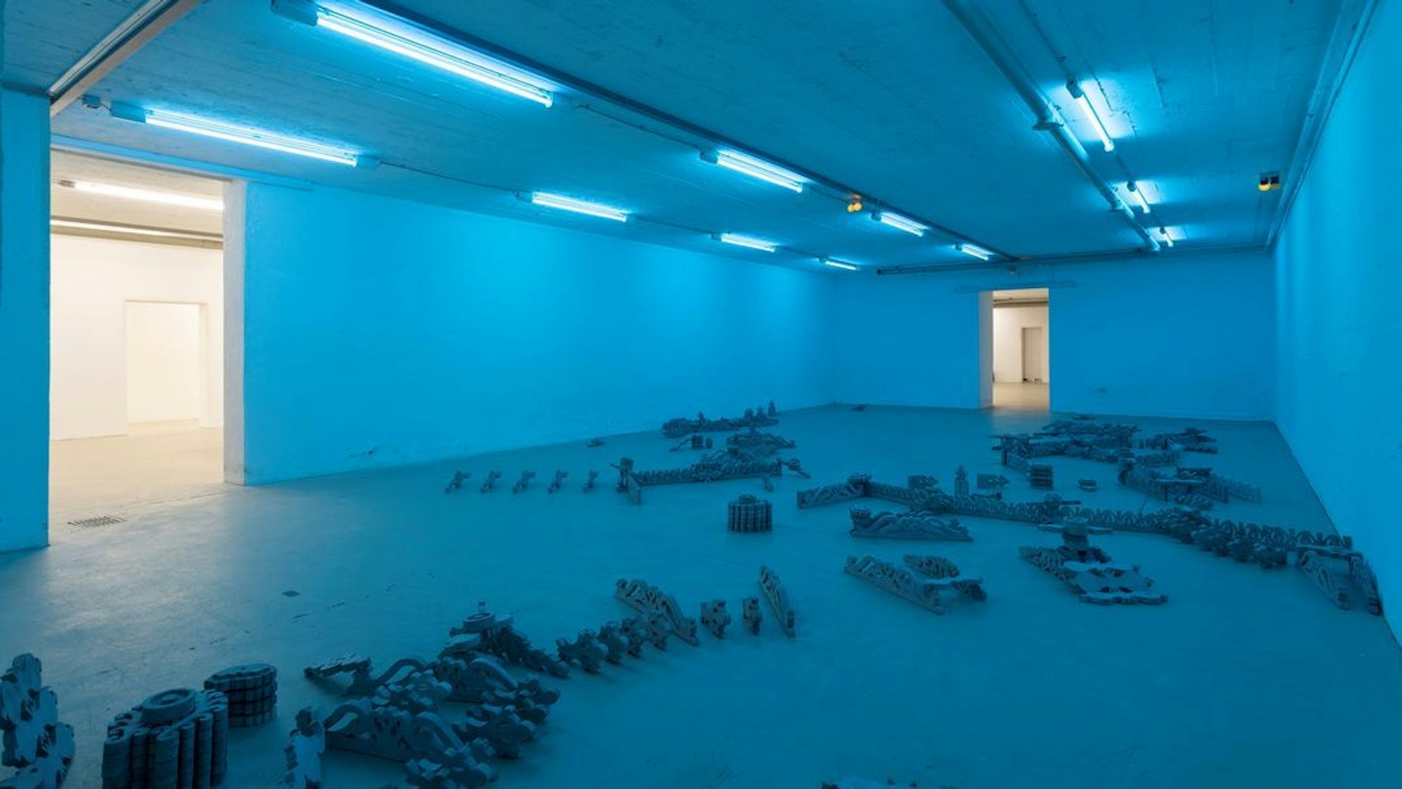 In einem blau beleuchteten Raum liegen Gegenstände auf dem Boden.