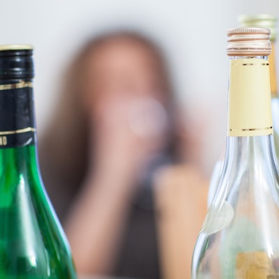 Leere Weinflaschen, im Hintergrund unscharf ein Gesicht.