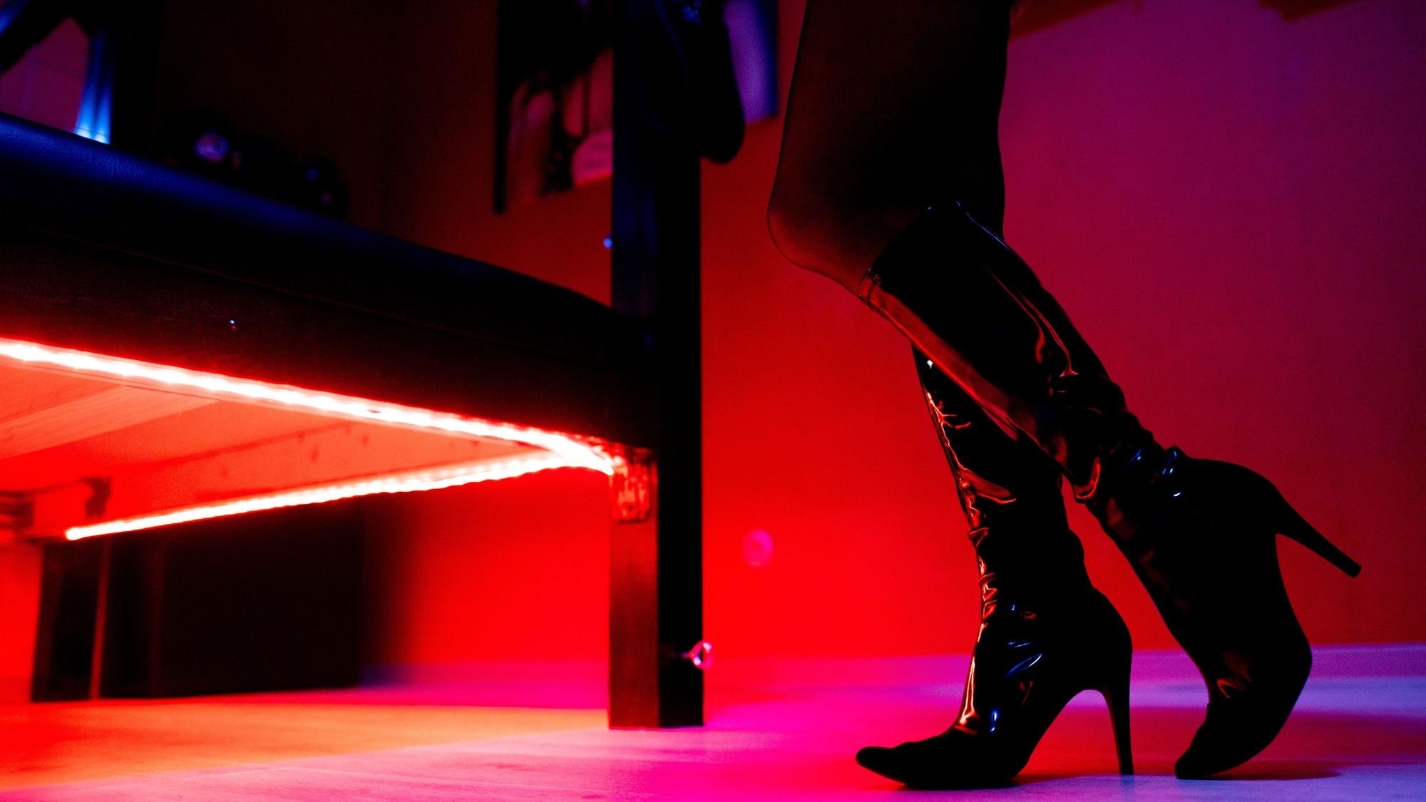 Eine Prostituierte steht vor der roten Beleuchtung unter einem Bett in einem Studio.