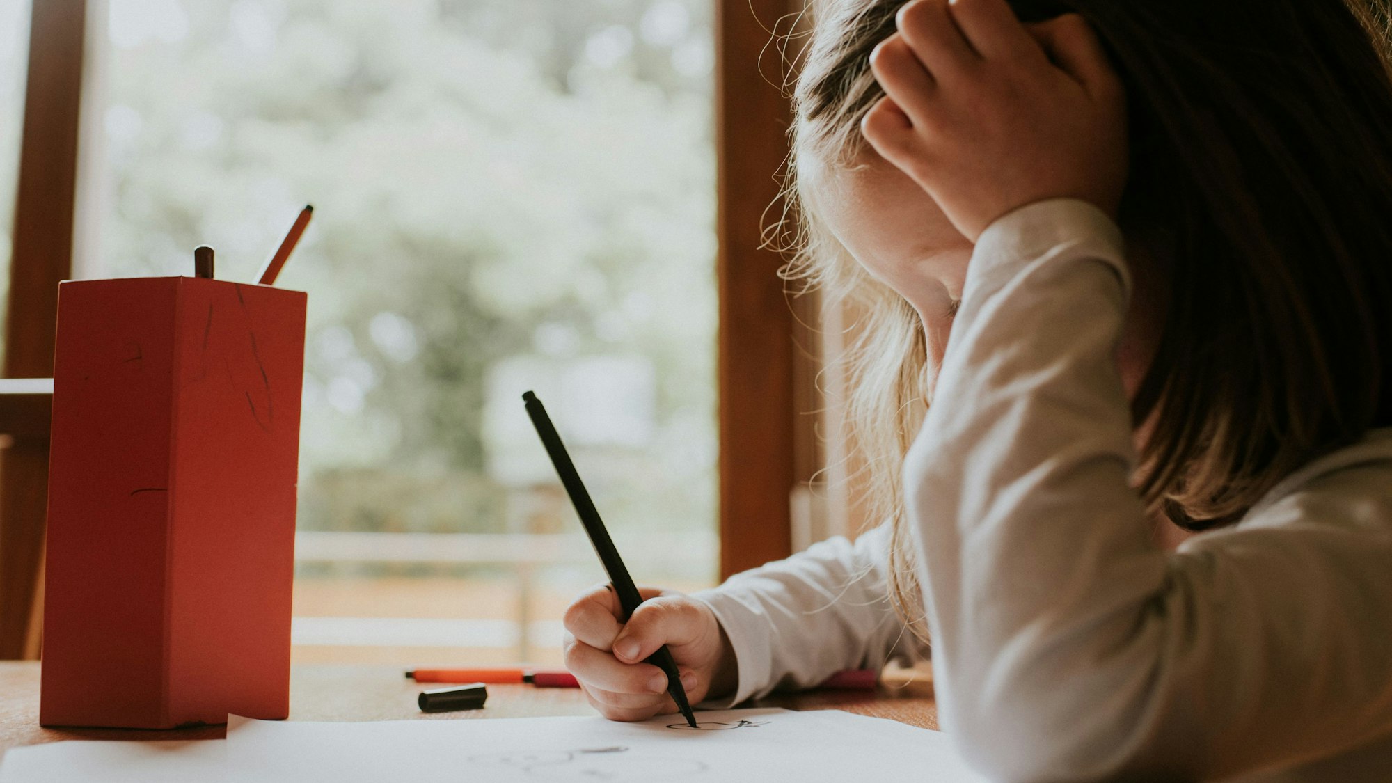 Ein Mädchen am Schreibtisch stützt ihren Kopf in die Hand.
Catherine Falls Commercial
Getty Images