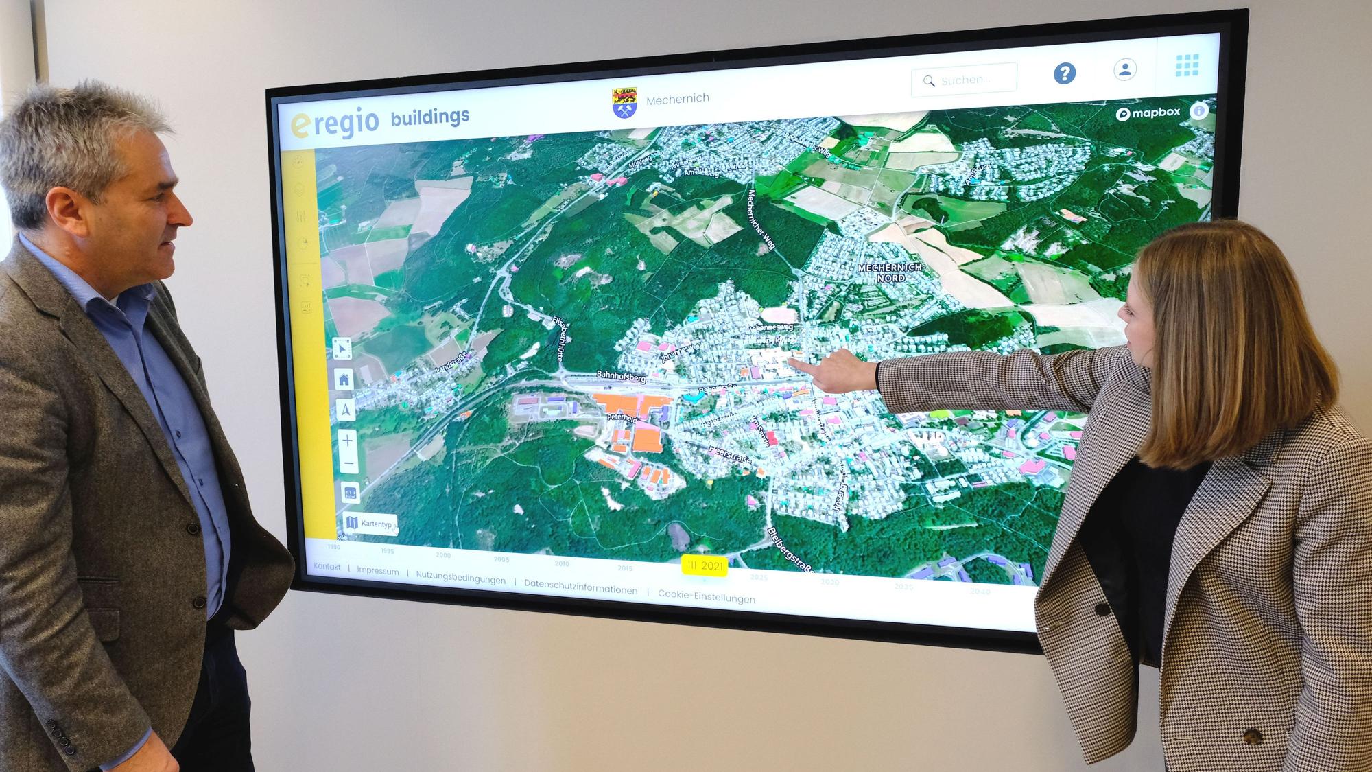 Geschäftsführer Markus Böhm und Mitarbeiterin Miriam Stork vom Euskirchener Energieversorger e-regio vor einer Ansicht des digitalen Zwillings zur Erstellung der Kommunalen Wärmeplanung für die Stadt Mechernich.