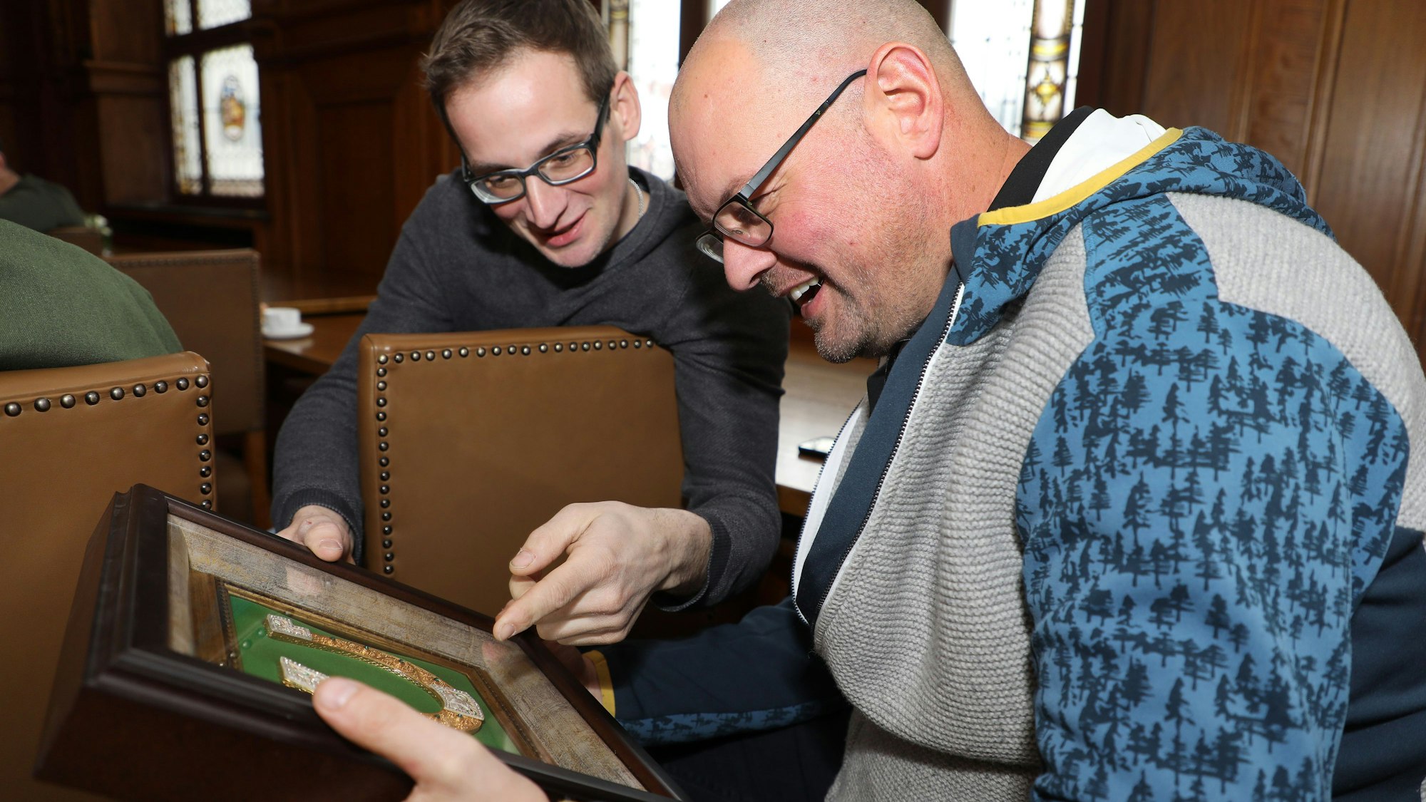 Die Hilfskonvoifahrer und -organisatoren Timo Stein und Niklas Habers schauen sich das prunkvolle Hufeisen an, das die Delegation aus Butscha der Partnerstadt Bergisch Gladbach mitgebracht hat.