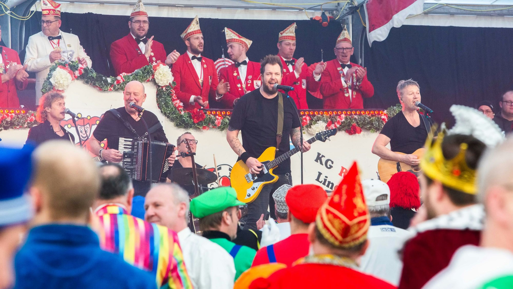 Eine Karnevalsband auf der Bühne, dahinter der Elferrat, vorn Zuschauer.