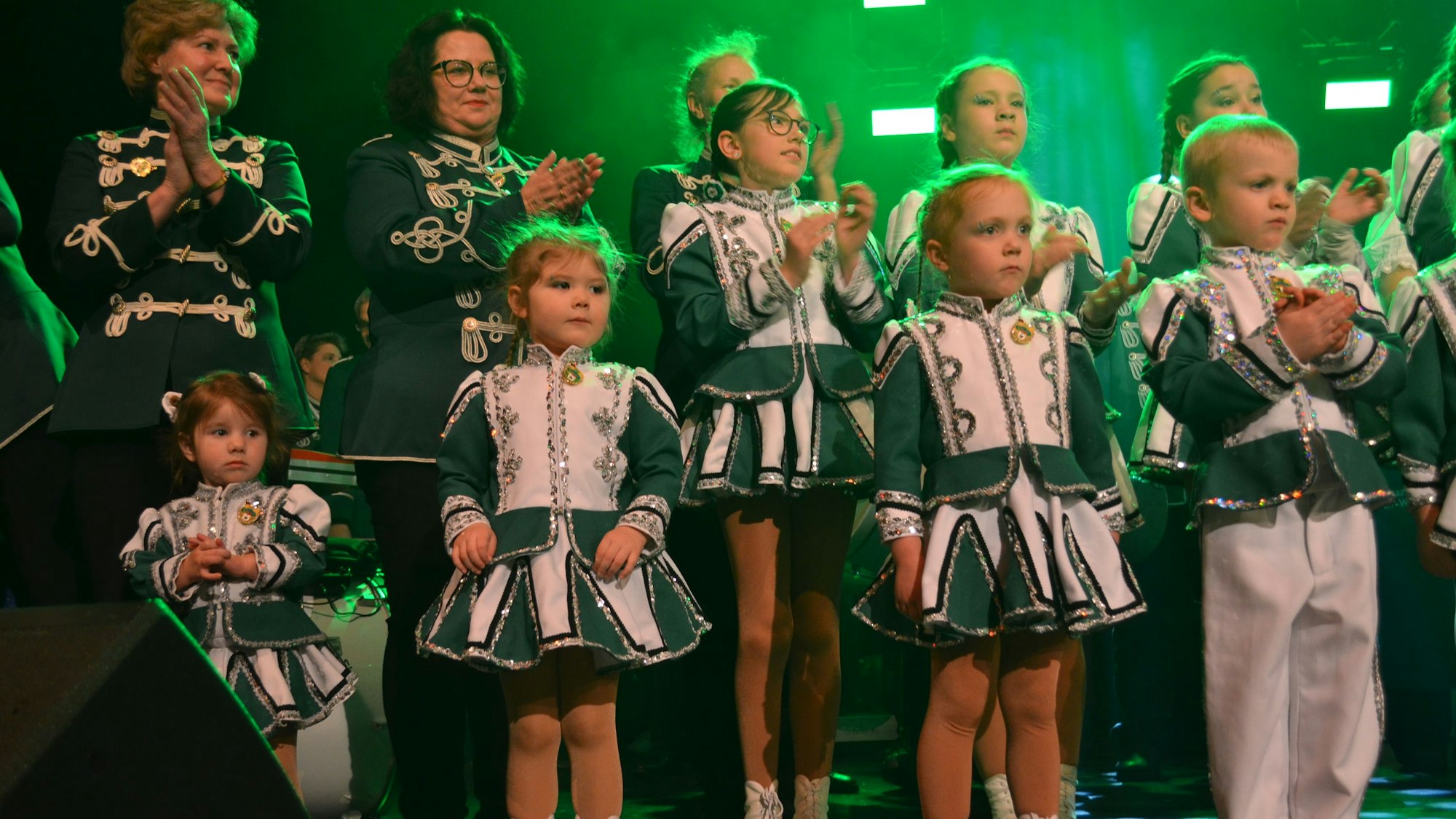 Mädchen und Jungs in den Uniformen der Grün-Weißen stehen auf der Bühne und klatschen.