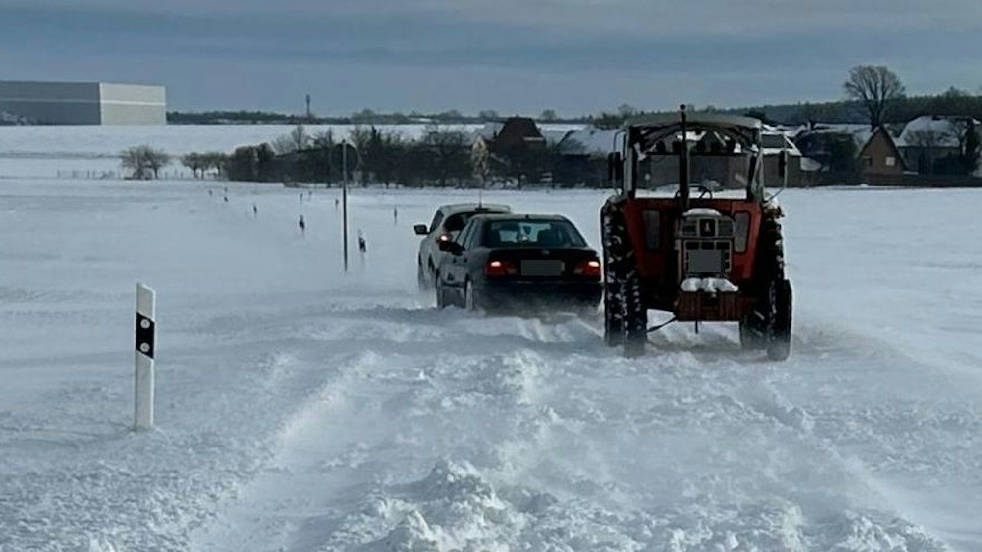 Mit einem Traktor werden zwei steckengebliebene Autos freigeschleppt.