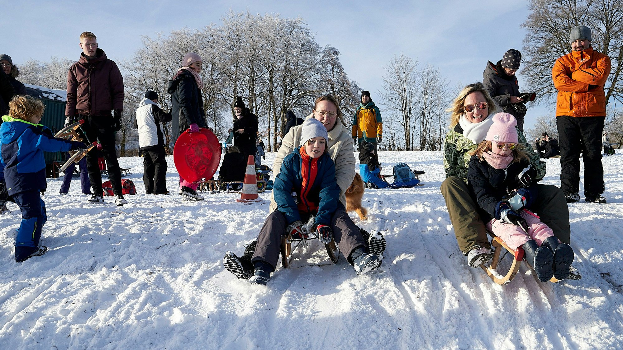 Zahlreiche Besucher rodeln den Abhang hinunter.