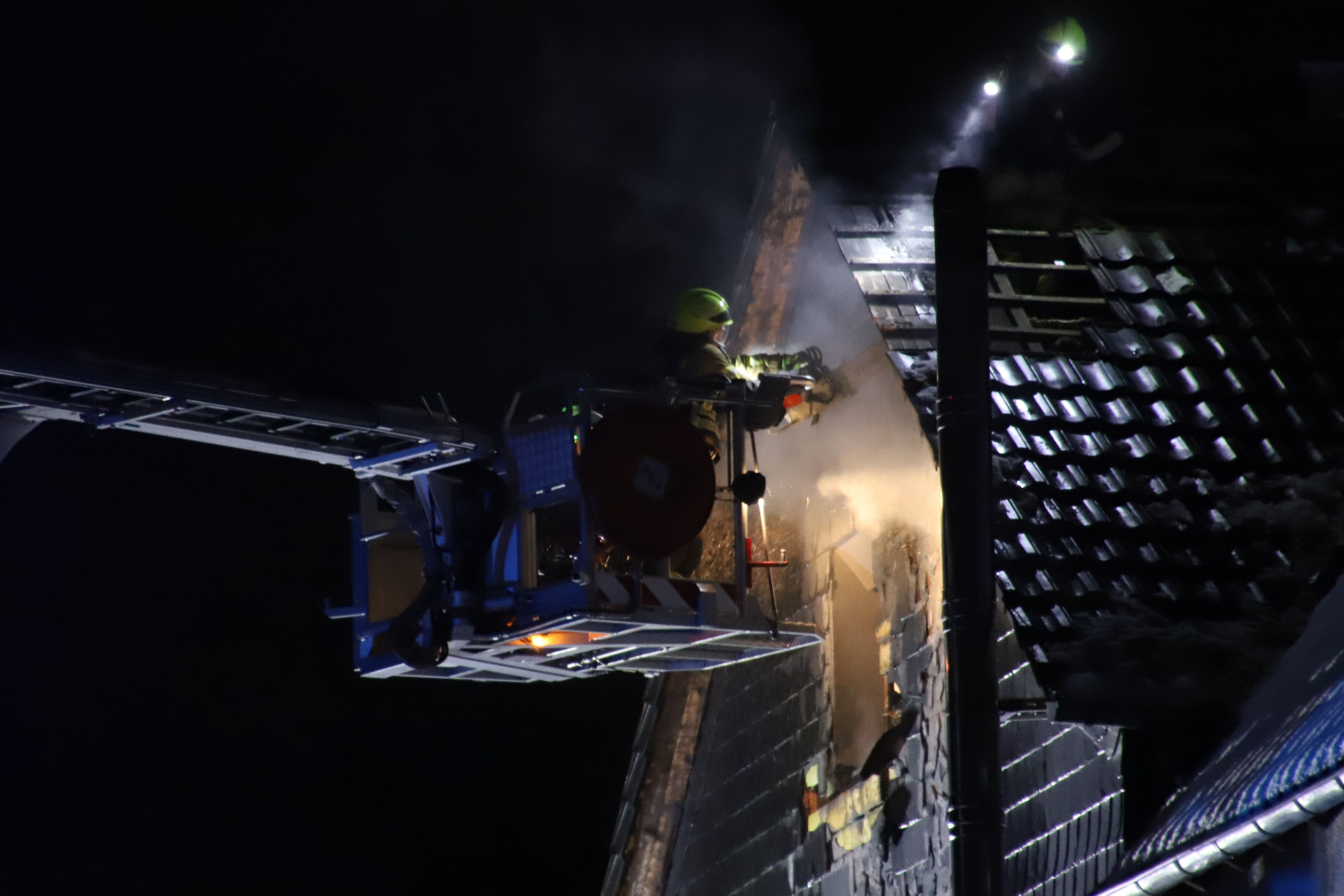 Ein Feuerwehrmann durchschnitt mit einer Motorsäge Verkleidung und Holzbalken. um letzte Glutnester zu finden.
