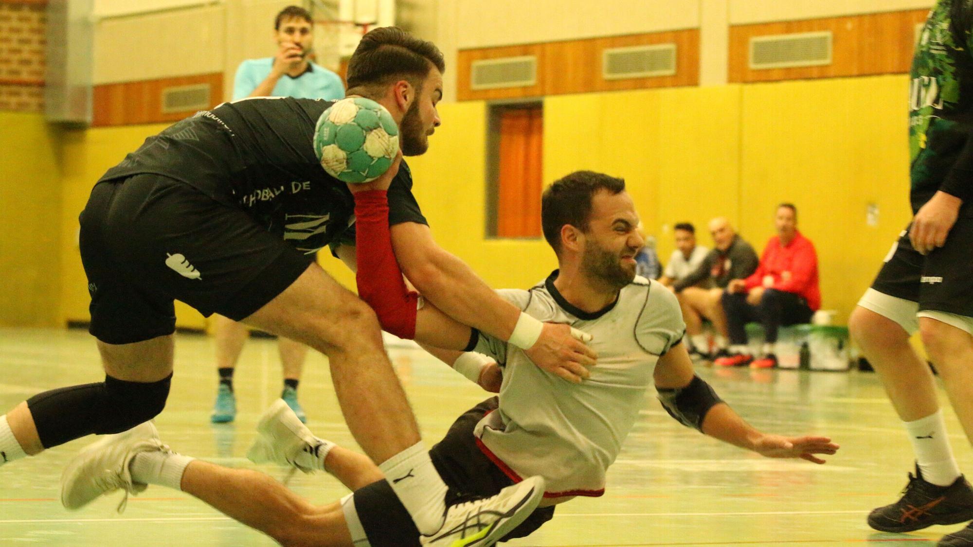 Dennis Schüller beim Sprungwurf. Er liegt fast auf dem Boden dabei. Sebastian Pohl hält ihn fest.