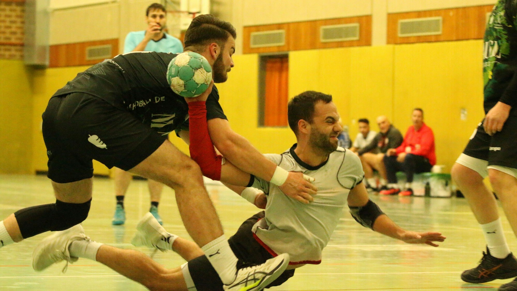 Dennis Schüller beim Sprungwurf. Er liegt fast auf dem Boden dabei. Sebastian Pohl hält ihn fest.