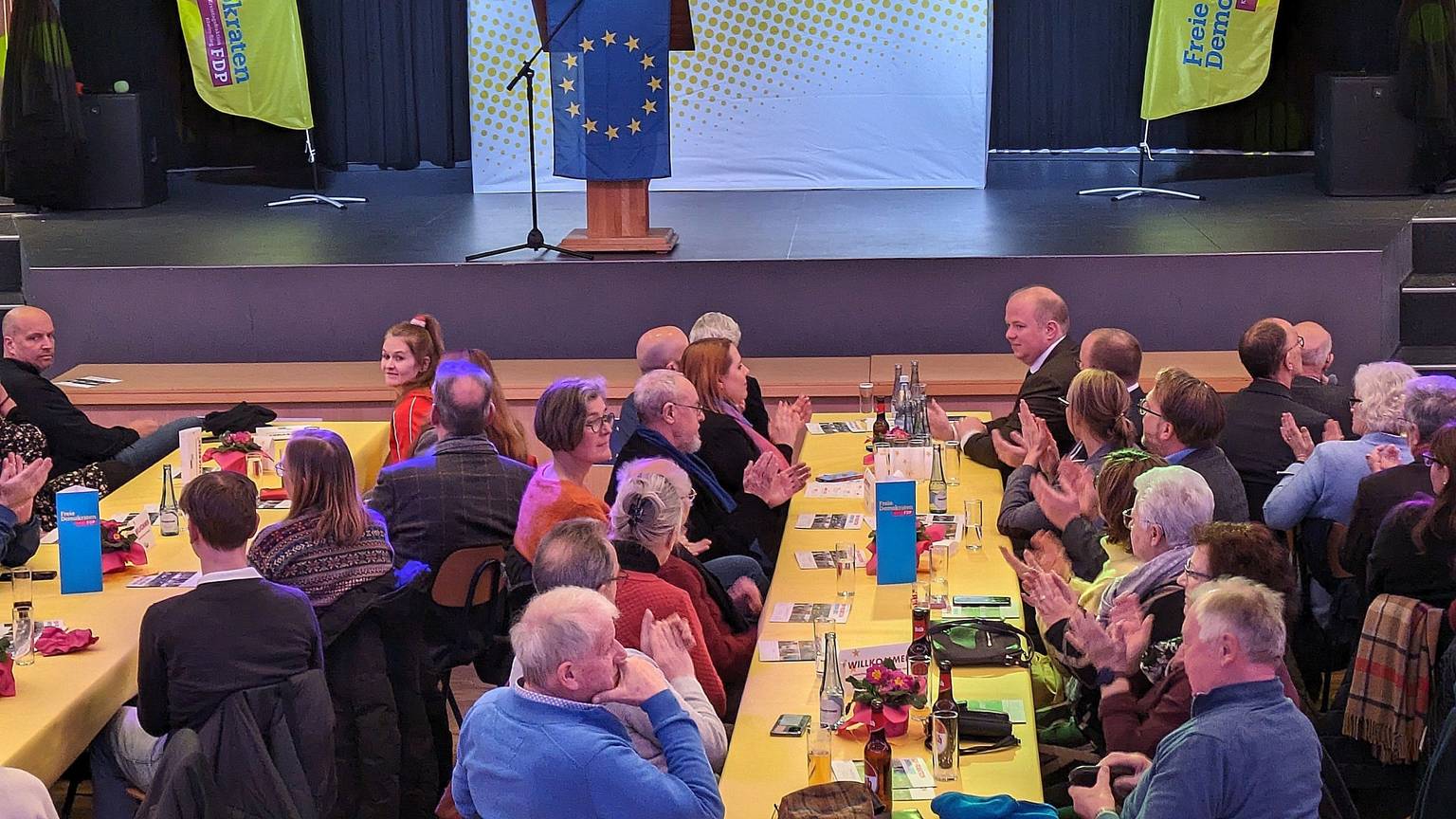 Eine Veranstaltung der FDP; auf der Bühne streht eine Frau am Rednerpult hinter einer Europafahne.