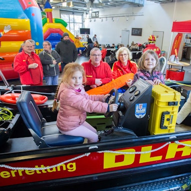 Das Foto zeigt das Rettungsboot der DLRG Wipperfürth mit drei Kindern und Ehrenamtlern der DLRG im Hintergrund.