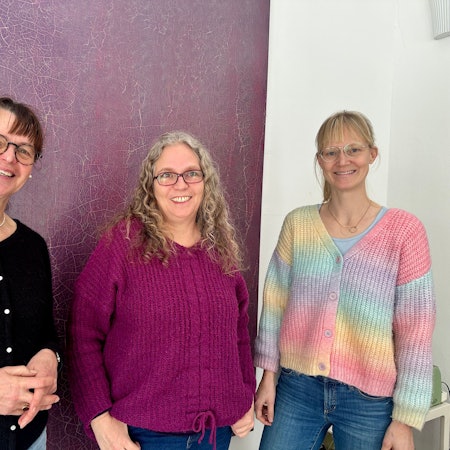 Drei Frauen stehen vor einer Wand.