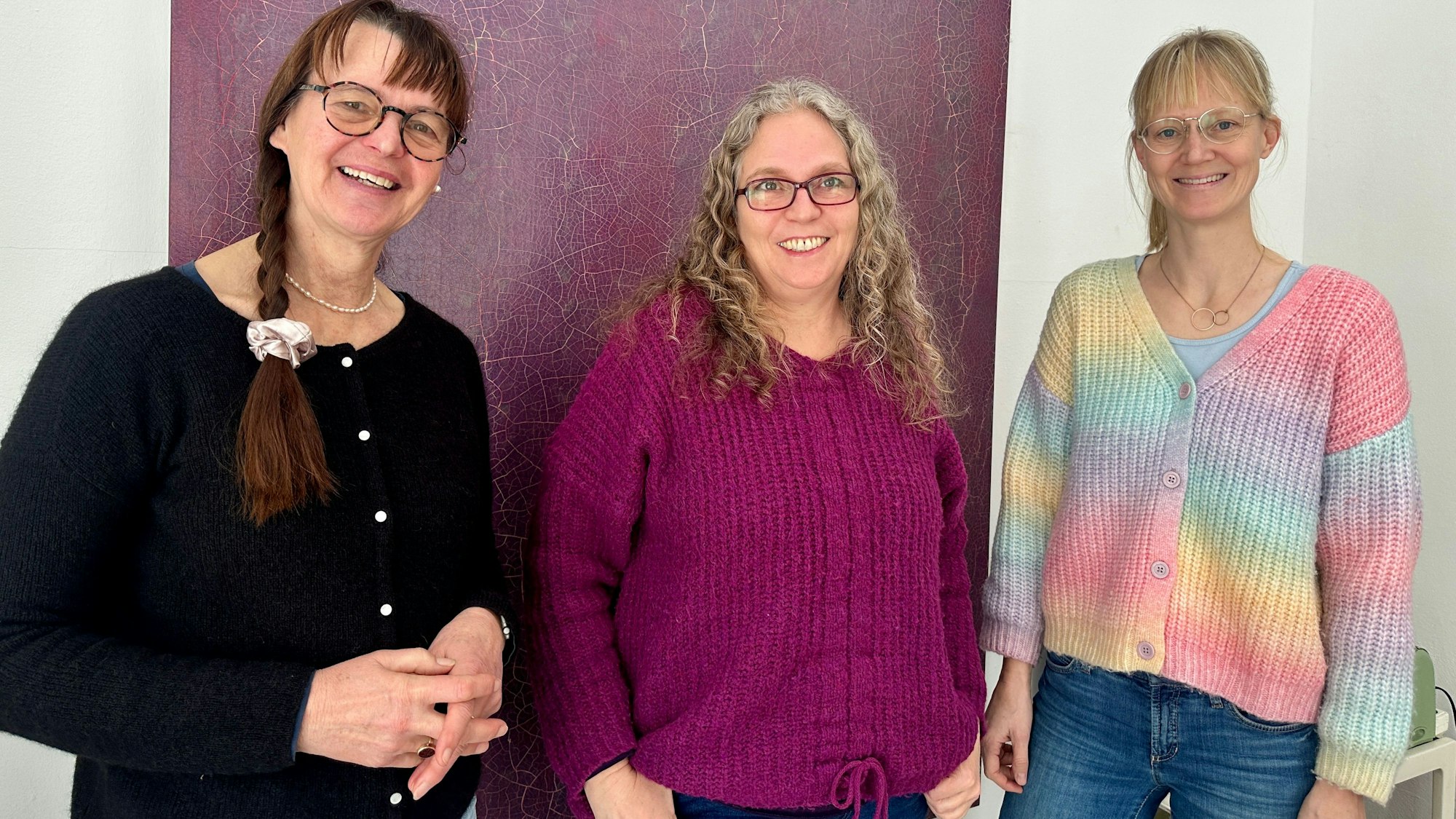 Drei Frauen stehen vor einer Wand.