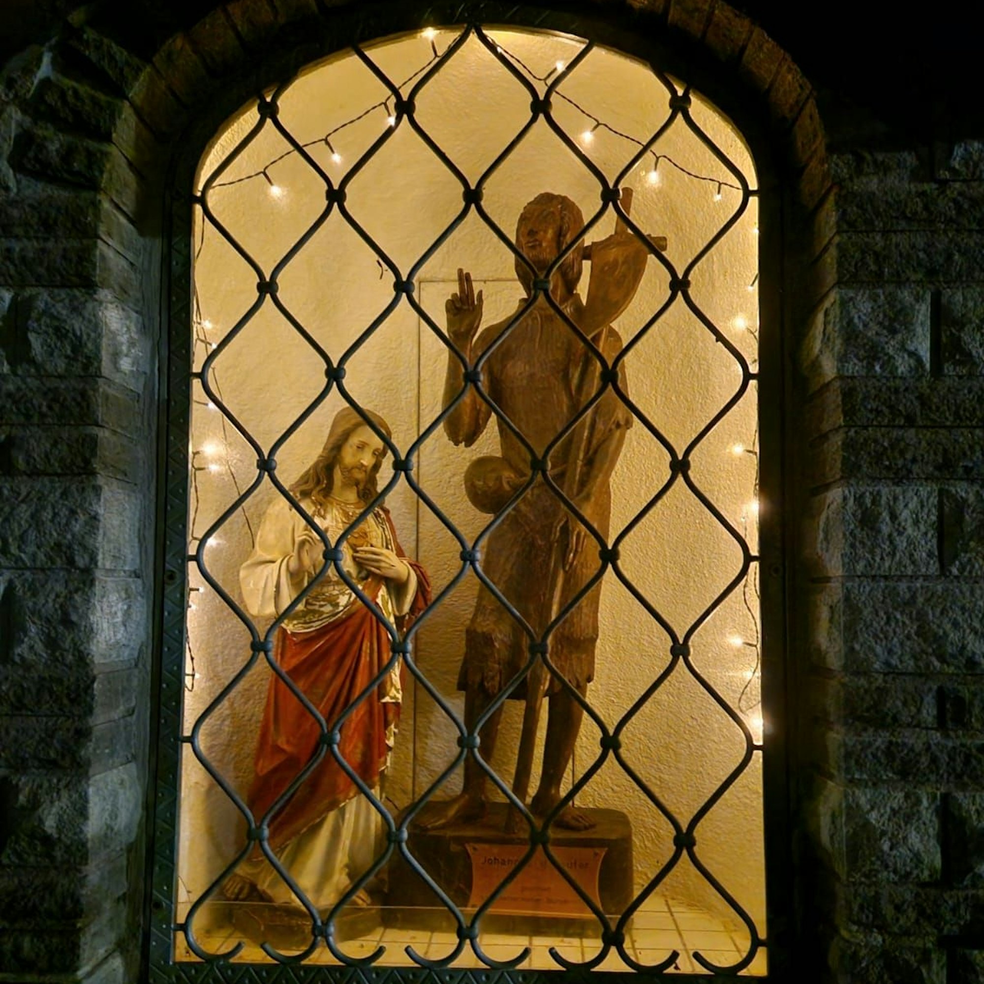 Die Jesusfigur und die Johannesfigur stehen nebeneinander im Metternicher Dorfbrunnen.
