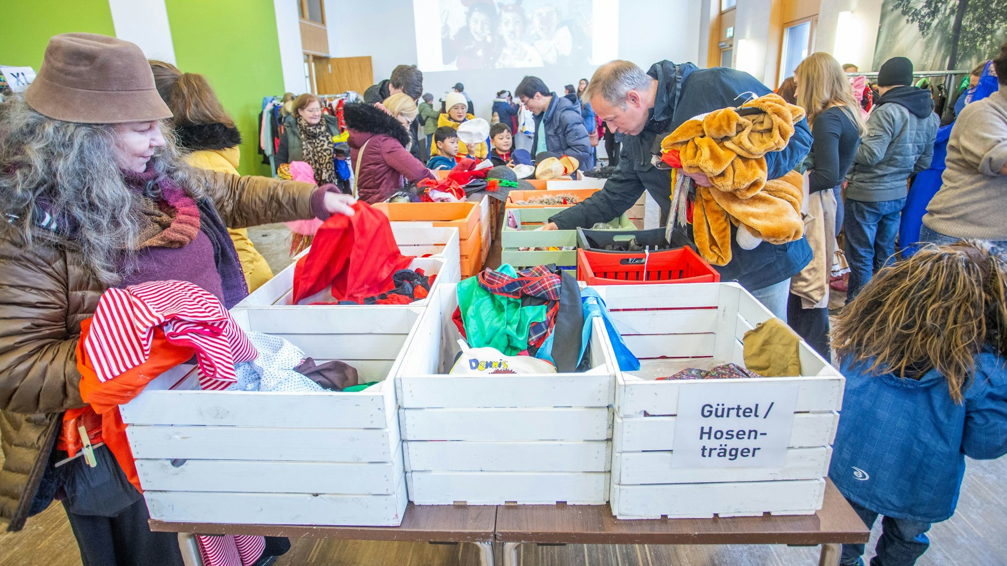 Mehrere Menschen stöbern in Kisten voller Karnevalskostüme.