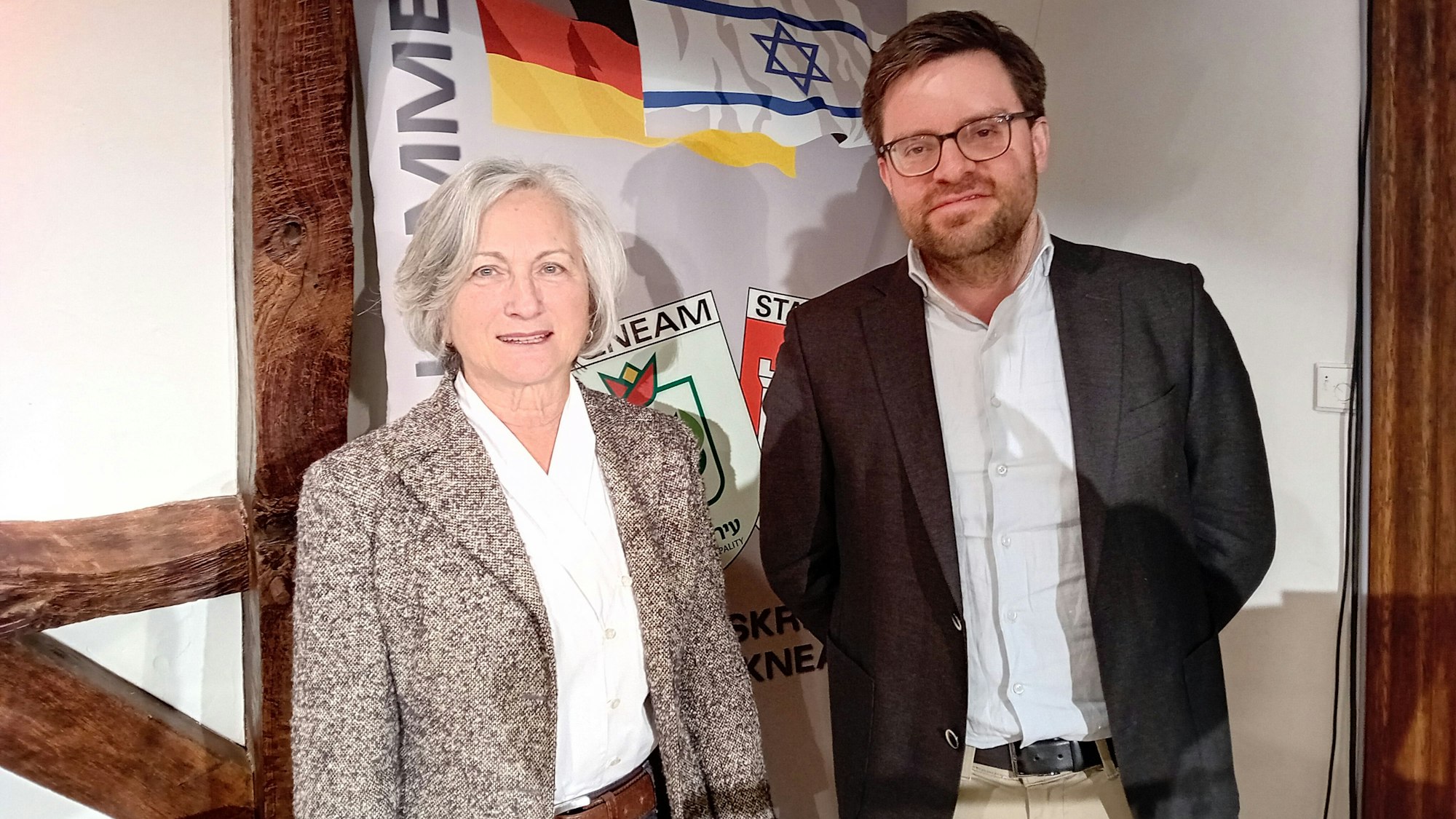 Eine Frau und ein Mann vor einem Transparent.