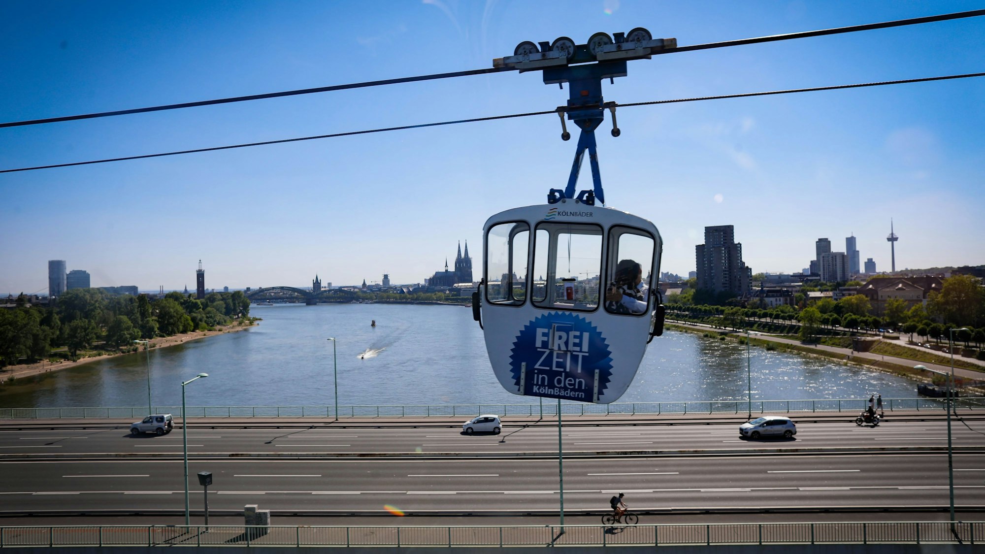 Eine Gondel der Kölner Bäder überquert den Rhein. Im Hintergrund der Kölner Dom und die Zoobrücke.